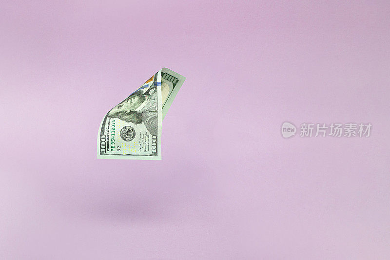 100美元钞票在粉红色的背景上飞舞。经济、储蓄和美元。一百美元。One hundred.
